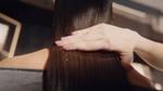Person's hand smoothing long straight hair.