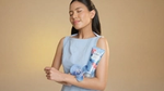 A person wearing a light blue sleeveless dress holds a tube of Citra body lotion