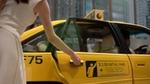 A person opening a yellow taxi door in the city.