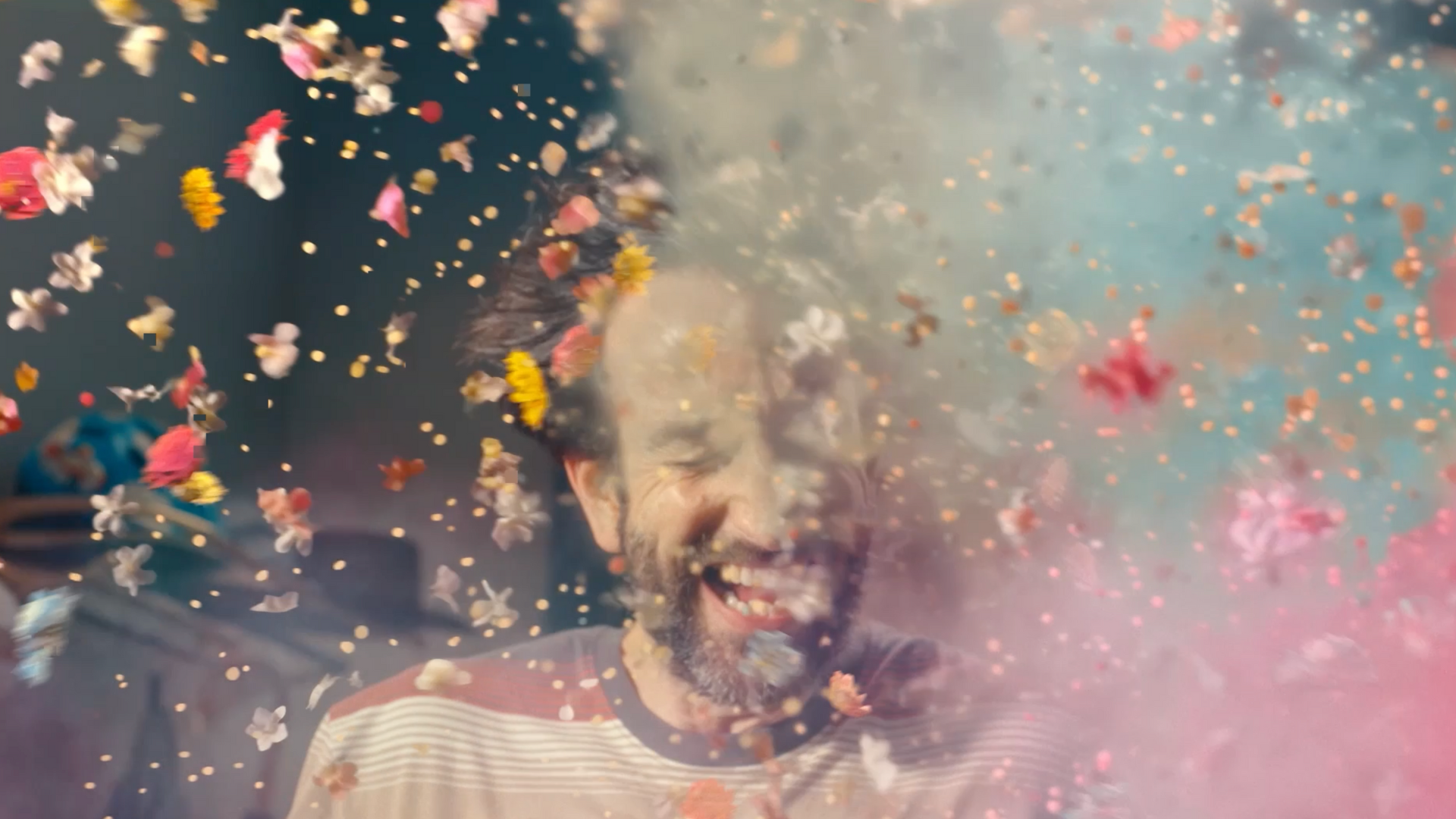 Laughing man surrounded by colorful flower petals.