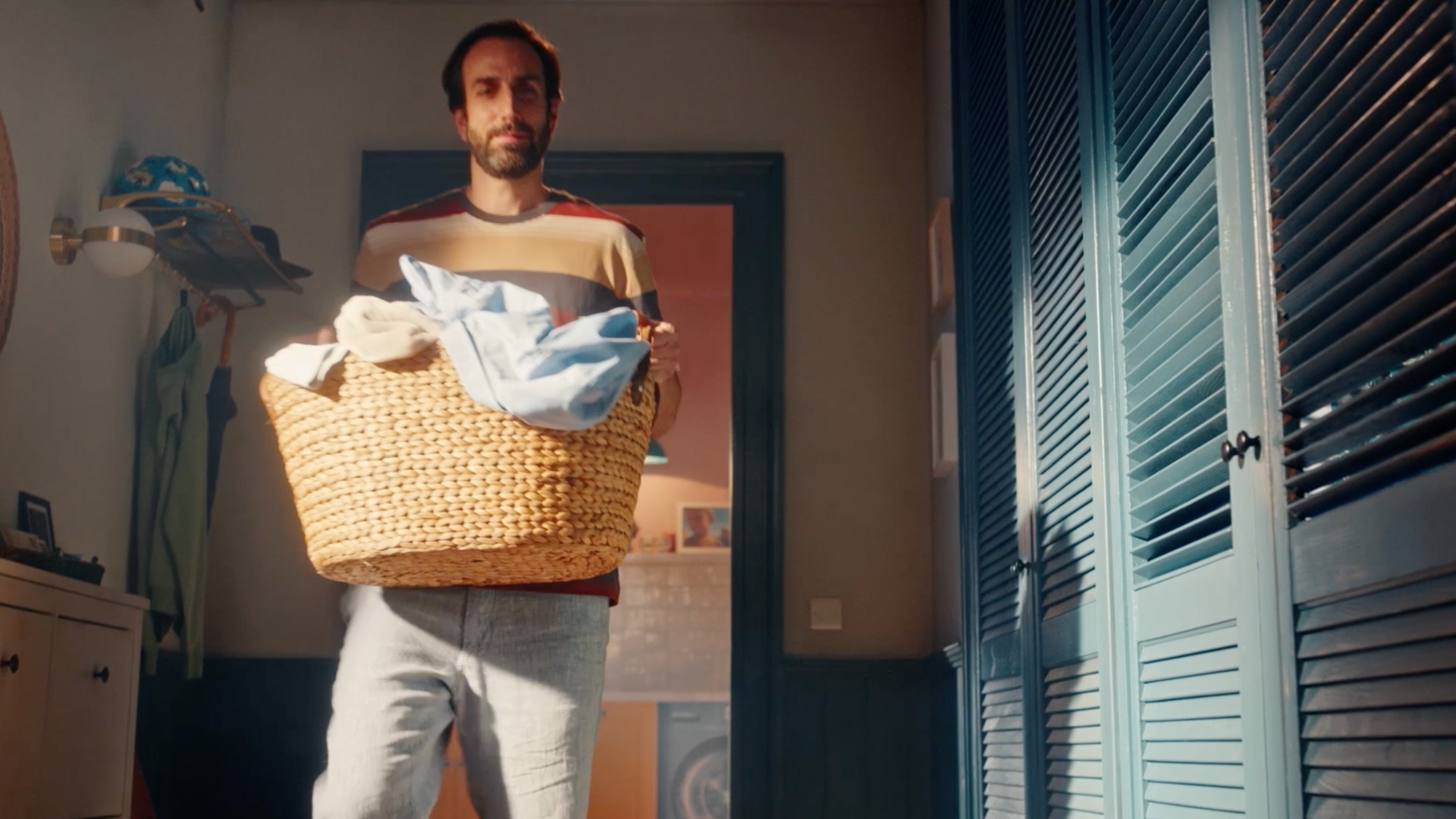 Man carrying a laundry basket in a room.