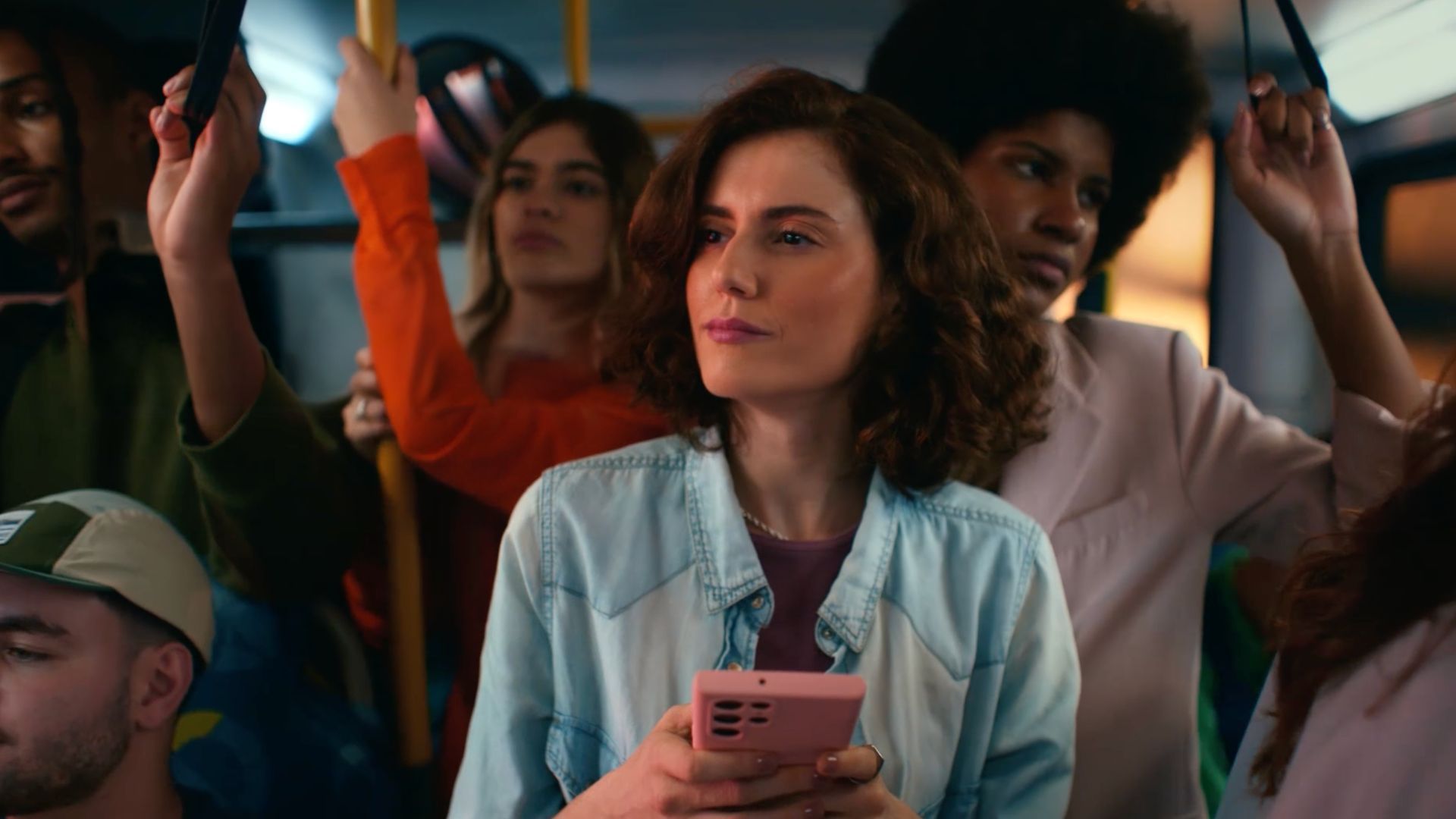 Woman holding phone on a crowded bus.