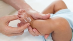 A person moisturising a babies foot