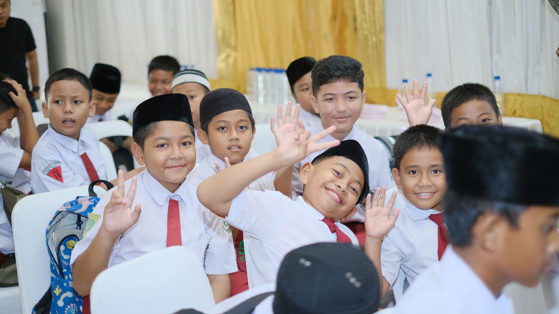 Smiling boys in uniforms with hats, posing and waving.