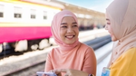 Two women smiling at a train station.