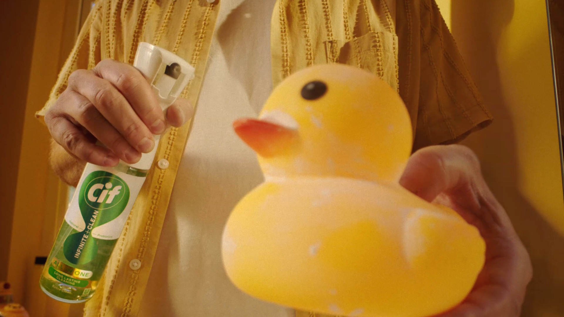 Person holding a yellow rubber duck and a Cif cleaning spray.