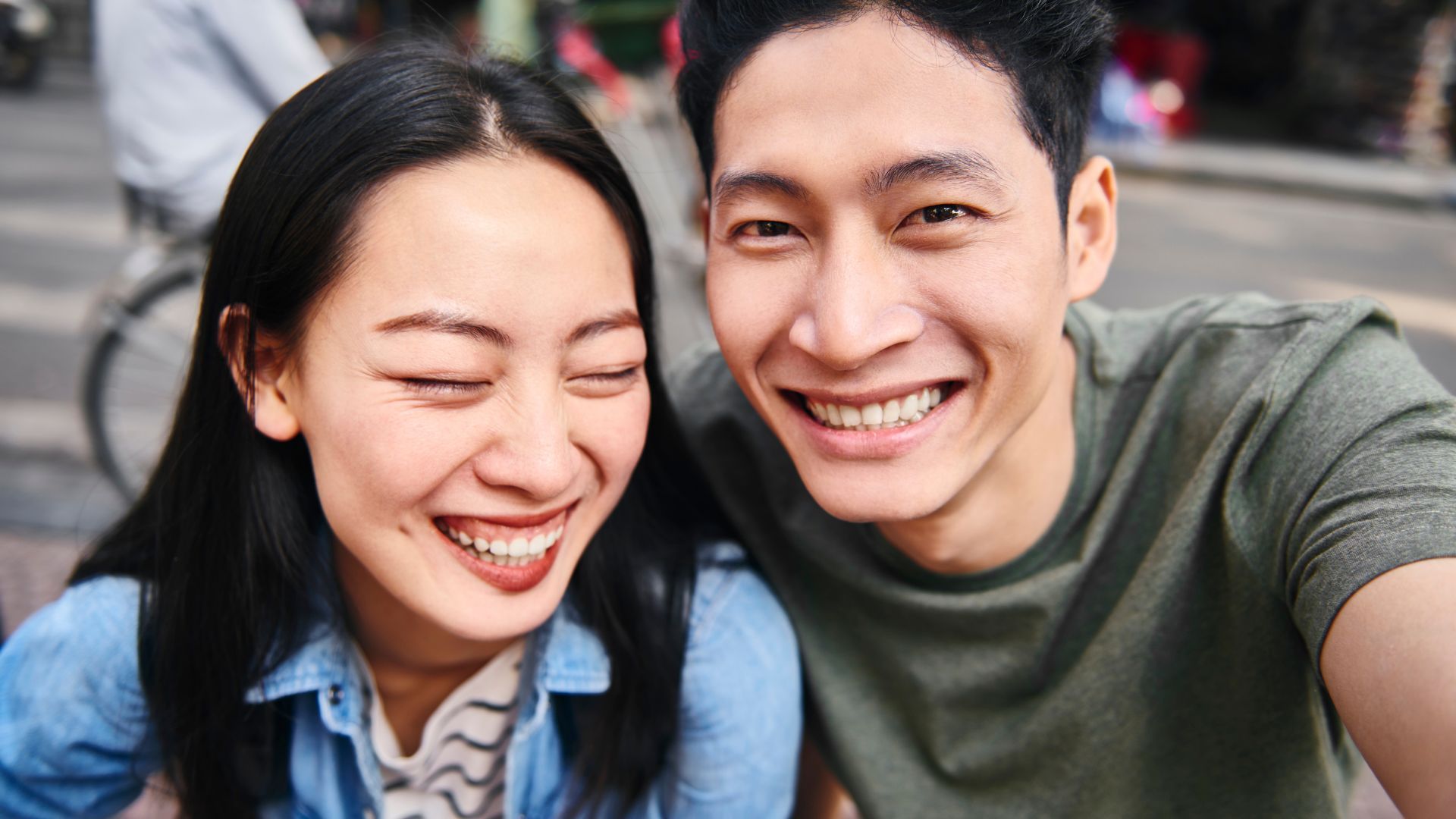 Smiling couple taking a selfie outdoors.