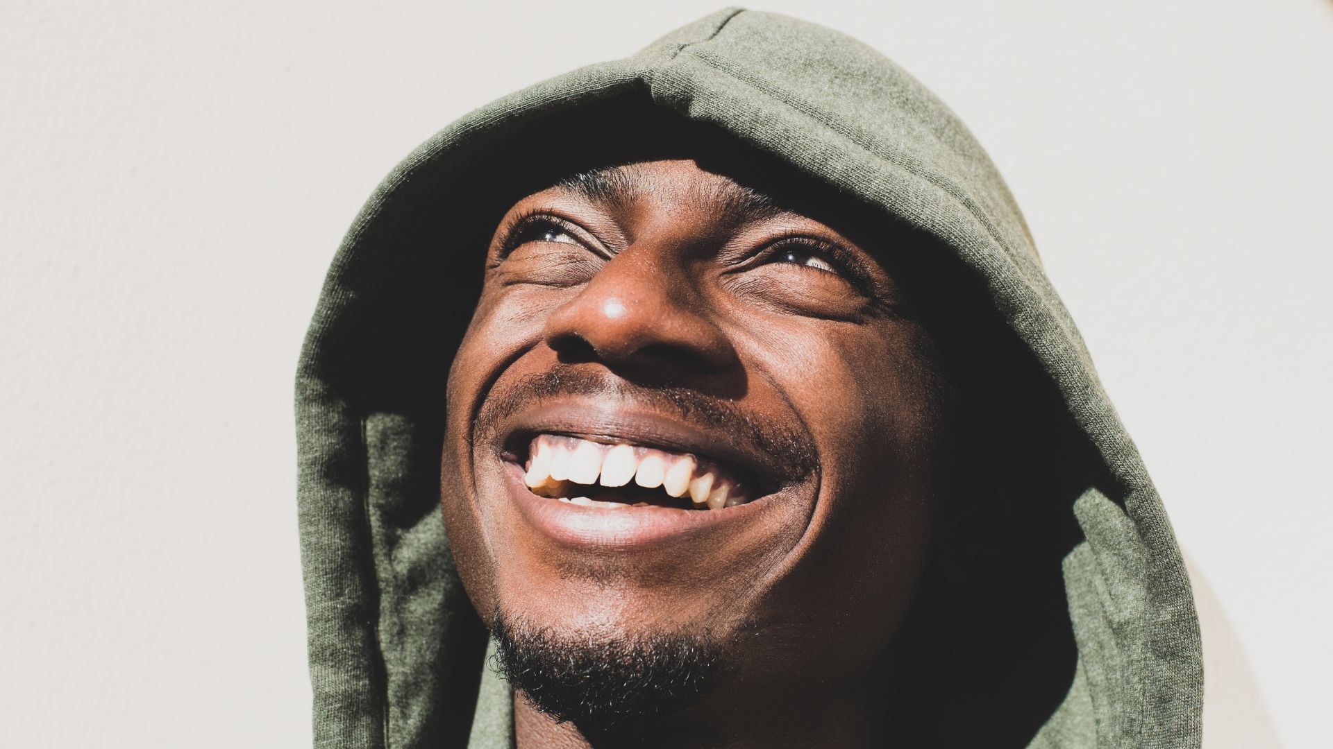 Person smiling brightly while wearing a hoodie.
