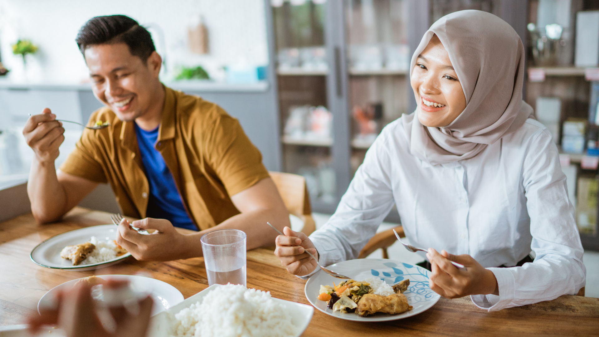 Two people enjoying a meal together at a wooden table.