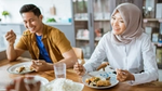 Two people enjoying a meal together at a wooden table.