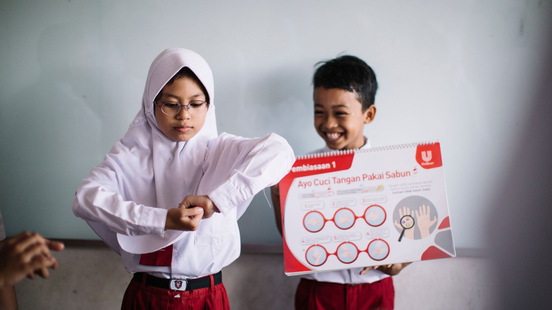 Children practicing hand washing in a classroom setting.