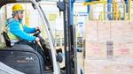 Fork lift truck driver moving a pallet of cardboard boxes labelled OMO in China