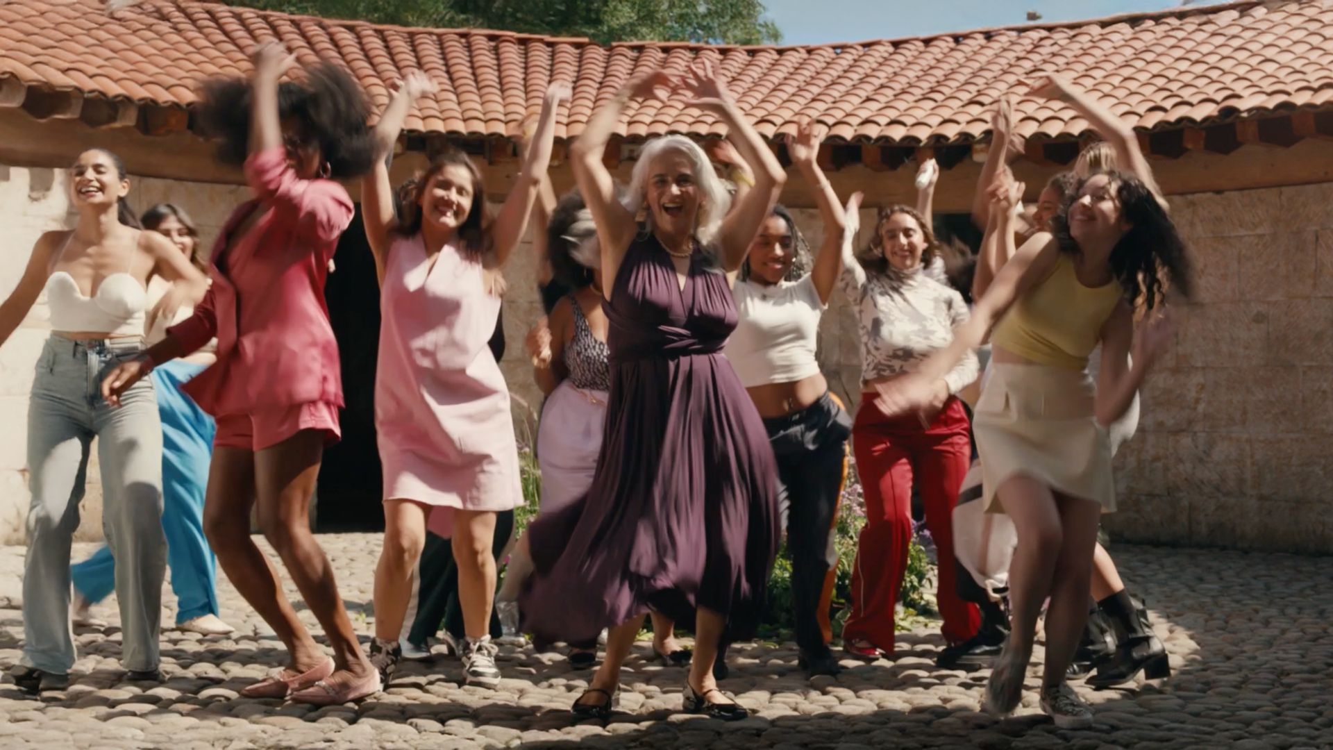 Group of people dancing joyfully outdoors.