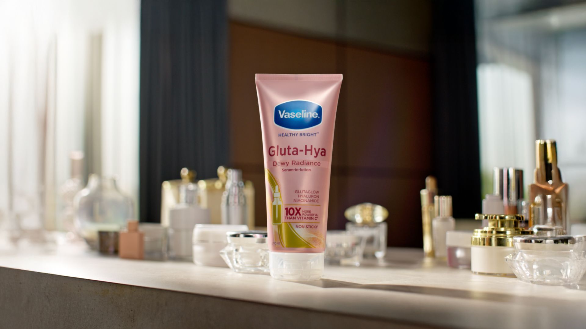 Vaseline Gluta-Hya Dewy Radiance lotion on a table with cosmetics.