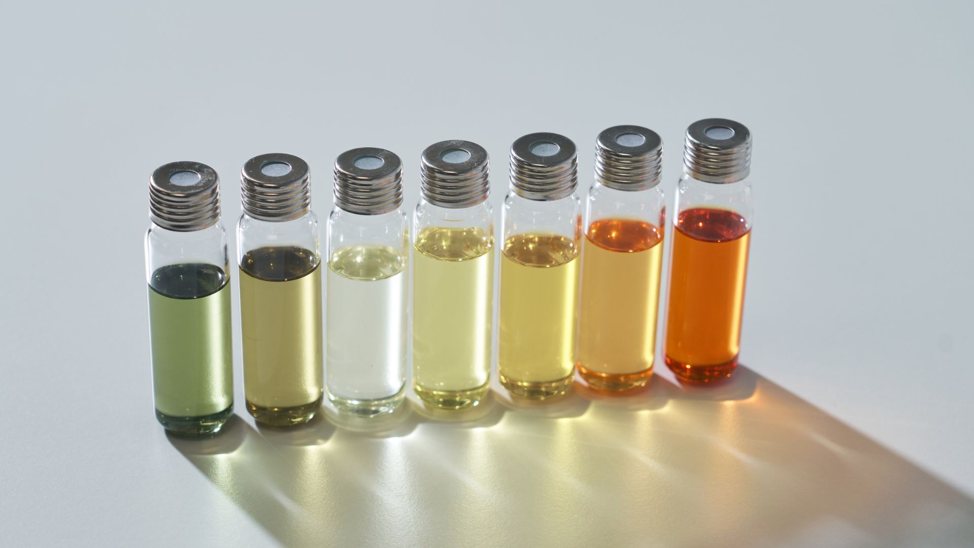 Seven vials with liquids in gradient colors from green to red.